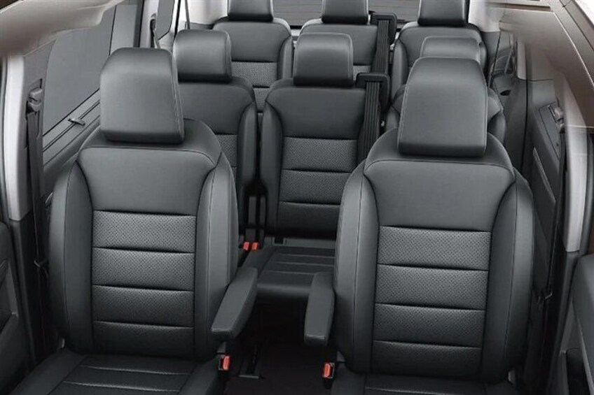 A car's rear seating area with black leather seats and a center console. 3