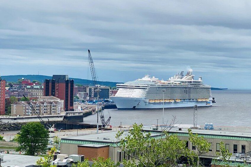 A large cruise ship docked at a port with cranes and buildings in the background. 2