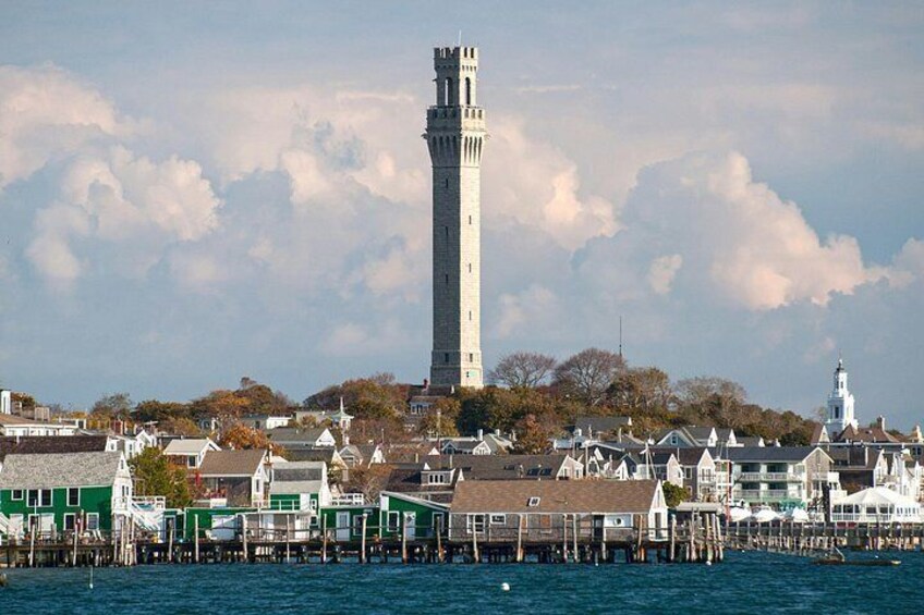 A coastal town with a prominent lighthouse, waterfront buildings, and a clear sky. 3