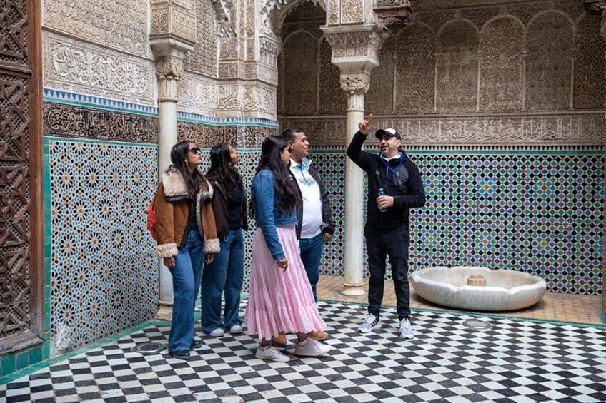 A group of people in a courtyard with intricate tile work and a fountain. 2