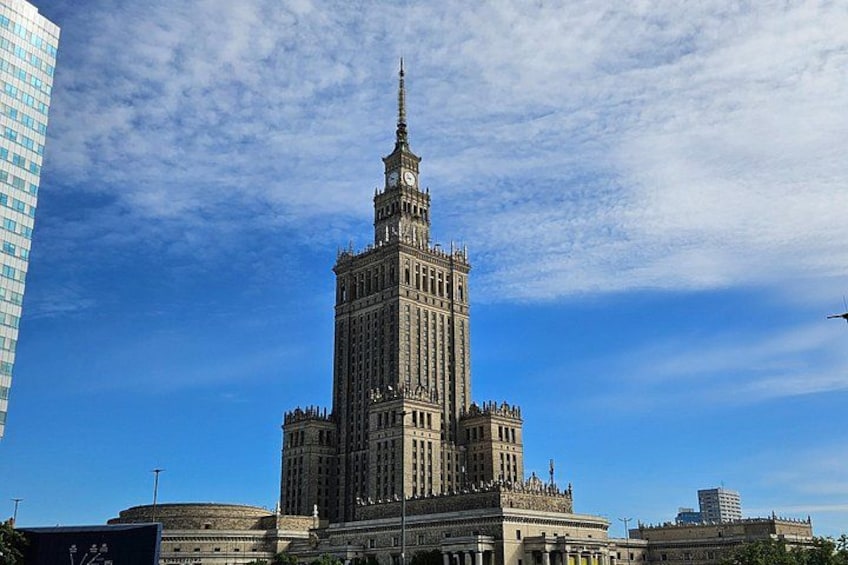 A historic building with a clock tower, surrounded by modern architecture. 1