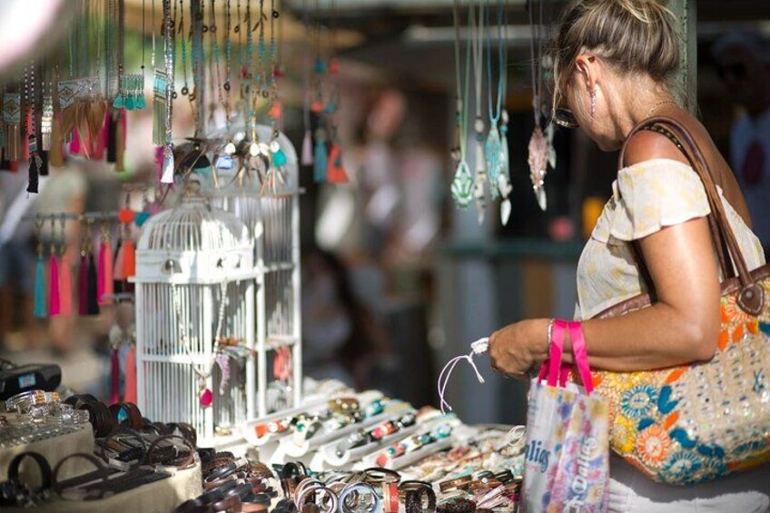 Un étal de marché où sont vendus des bijoux et une cage à oiseaux blanche. 1