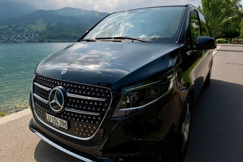Un SUV nero parcheggiato vicino a un lago, con montagne sullo sfondo. 2