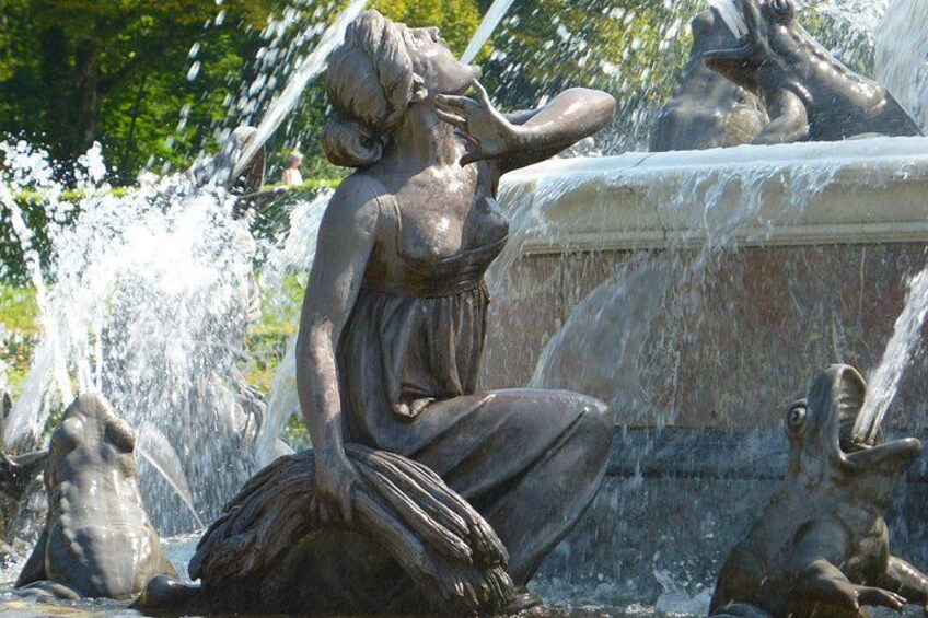 A statue of a woman with water flowing from her head, surrounded by other statues and water jets. 2