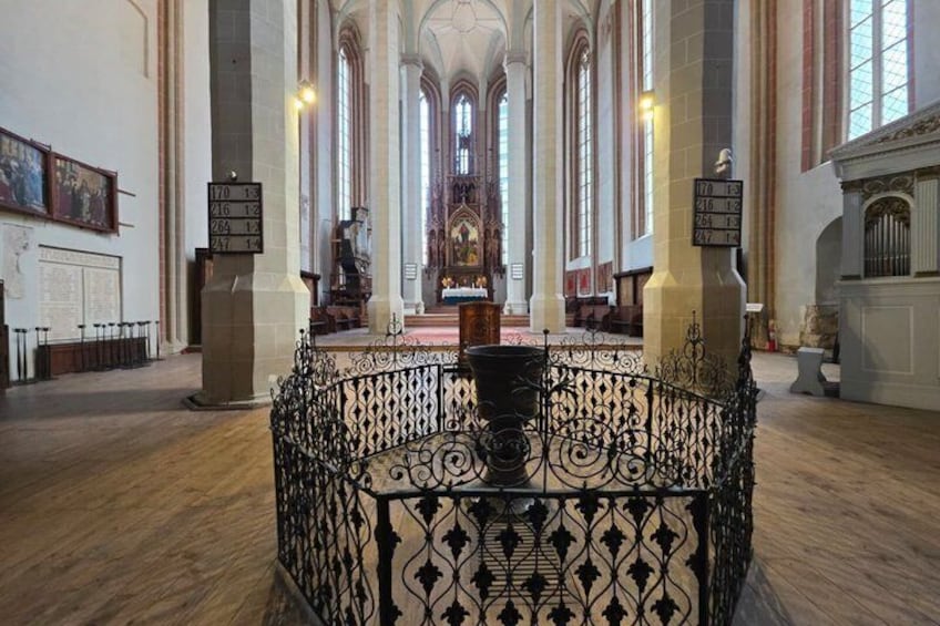 Interior de iglesia con un pasillo central, barandilla de metal negro ornamentada y un gran altar al fondo. 3