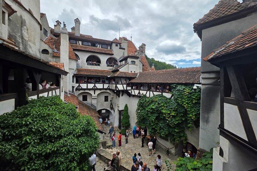 A courtyard with people, buildings with timber framing, and a hill in the background. 5