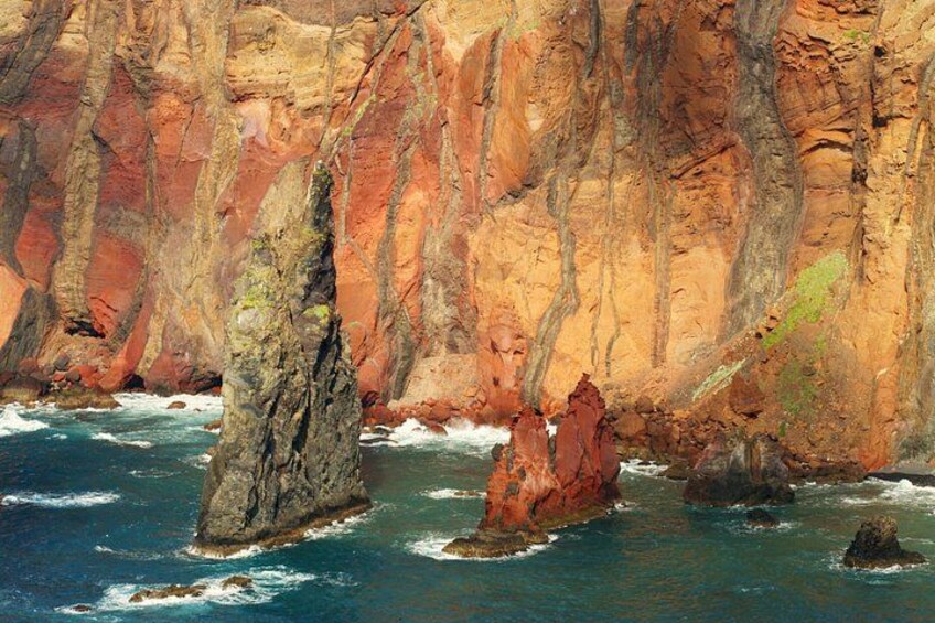 A coastal landscape with rocky cliffs and a large rock formation in the water. 3