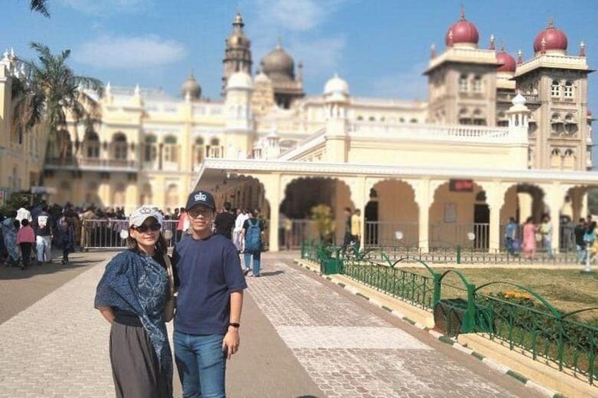 A historic building with domed towers and arches, a paved walkway, and a green fence. 3