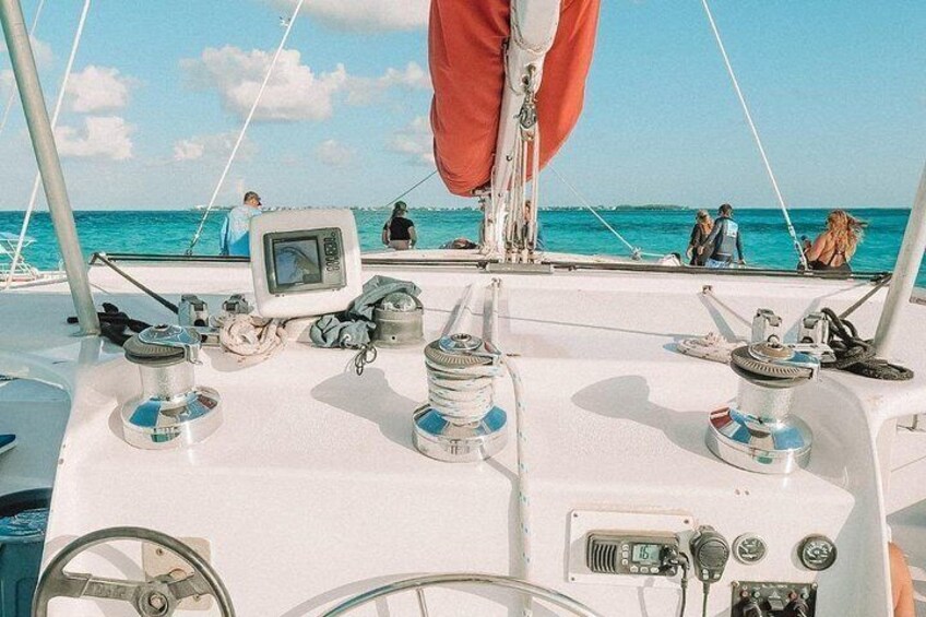 Le pont d’un bateau, équipé d’instruments de navigation, d’un gouvernail, et où se trouvent des personnes sur l’eau. 2