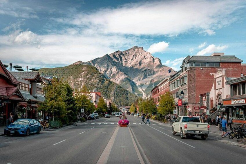 A mountain town street with cars, buildings, and a prominent mountain in the background. 3