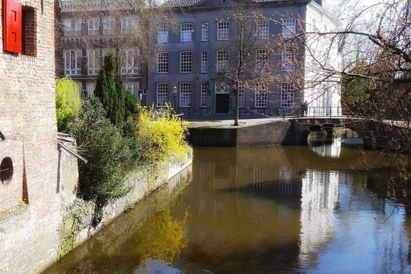 Een gracht met gebouwen, een brug en een boom die in het water wordt weerspiegeld. 2