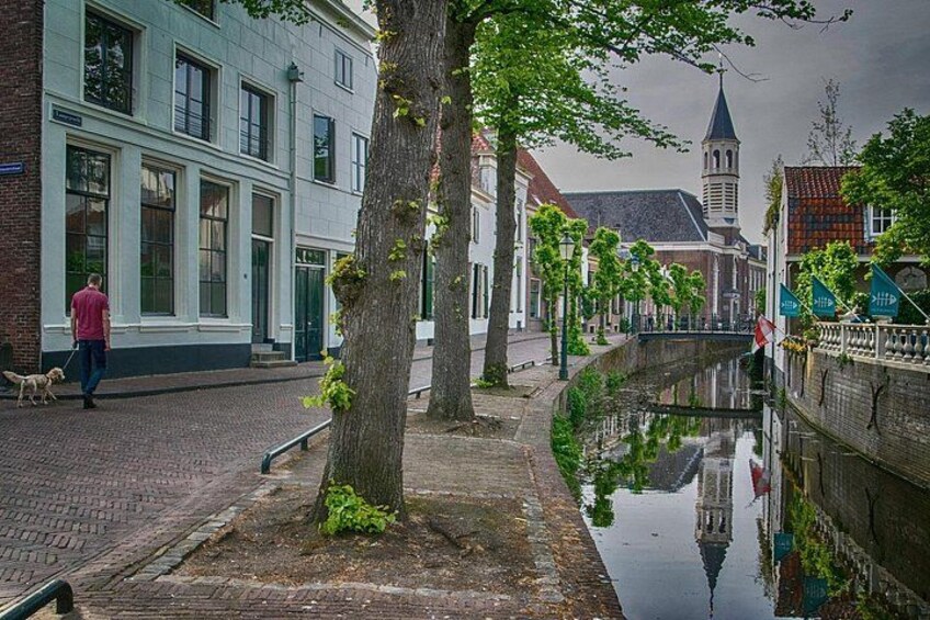 Een gracht met gebouwen, een hond en een persoon die aan het wandelen is. 5