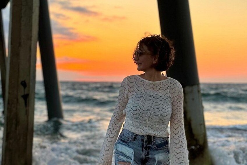 Una persona parada en un muelle con un atardecer de fondo. 1