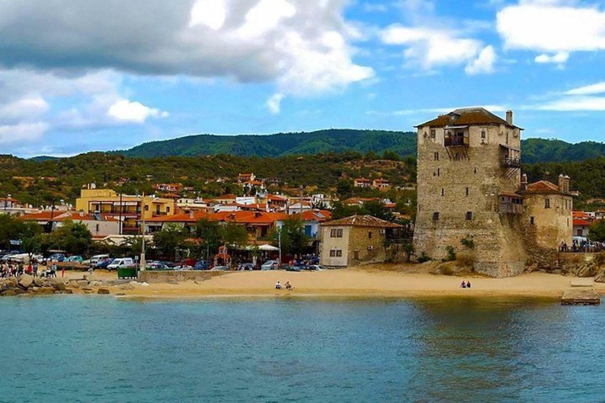A coastal town with a prominent tower, sandy beach, and buildings with red roofs. 2