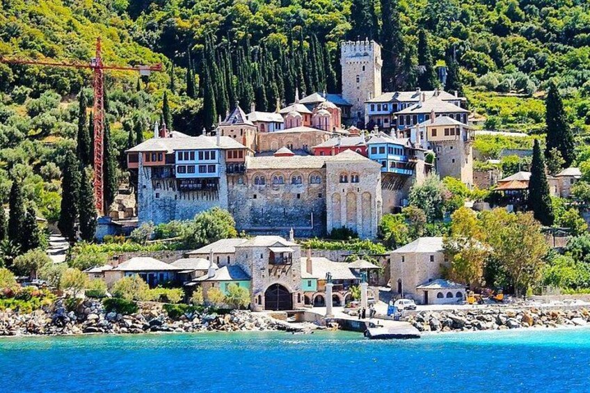 A coastal town with historic buildings, a castle, and a clear blue sea. 5