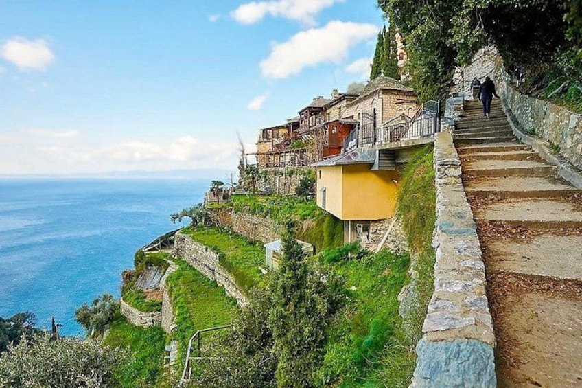 A coastal village with stone steps leading down to the sea, houses on the hillside, and a clear sky. 2