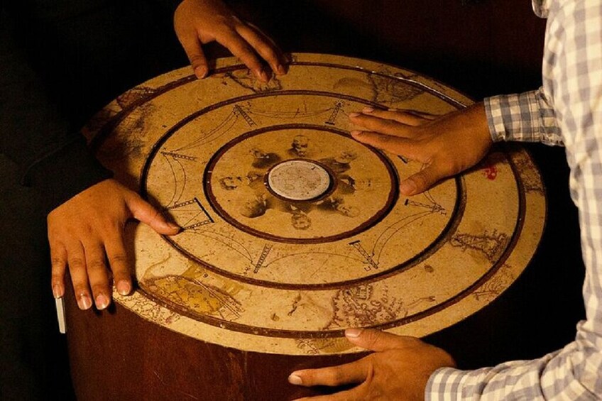 Iemand die een cirkelvormig, oud aanzien hebbend object met verschillende symbolen en teksten bedient. 3