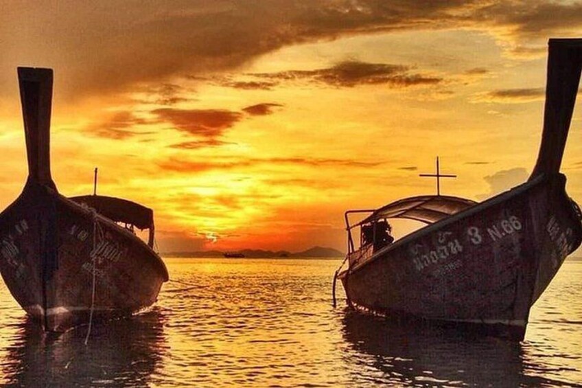 Two boats with inscriptions on their hulls, a sunset in the background, and calm water. 2