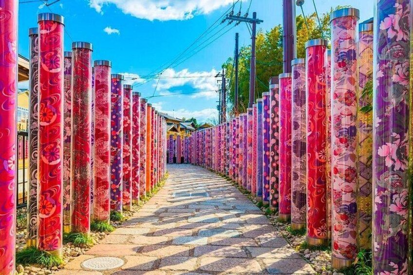 En sti kantet af høje, farverige cylindriske strukturer med blomstermønstre. 2