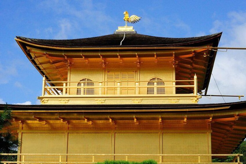 Een traditioneel Japans gebouw met een gebogen dak, een balkon met hekwerk en een gouden beeldhouwsel bovenop. 4