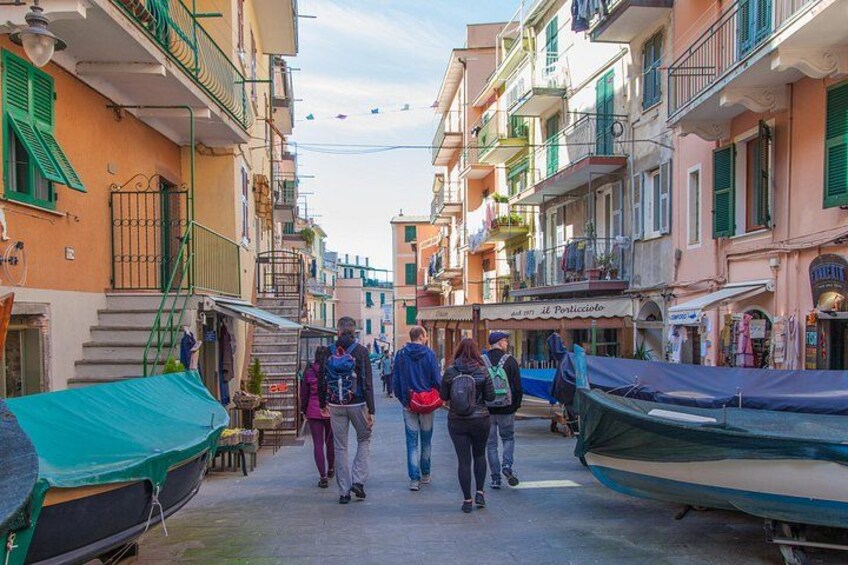 Una calle estrecha bordeada de edificios coloridos, un bote cubierto con una lona, y gente caminando. 3