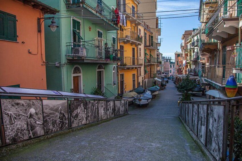 Una calle estrecha bordeada de edificios coloridos, un mural en la pared y barcos estacionados. 2