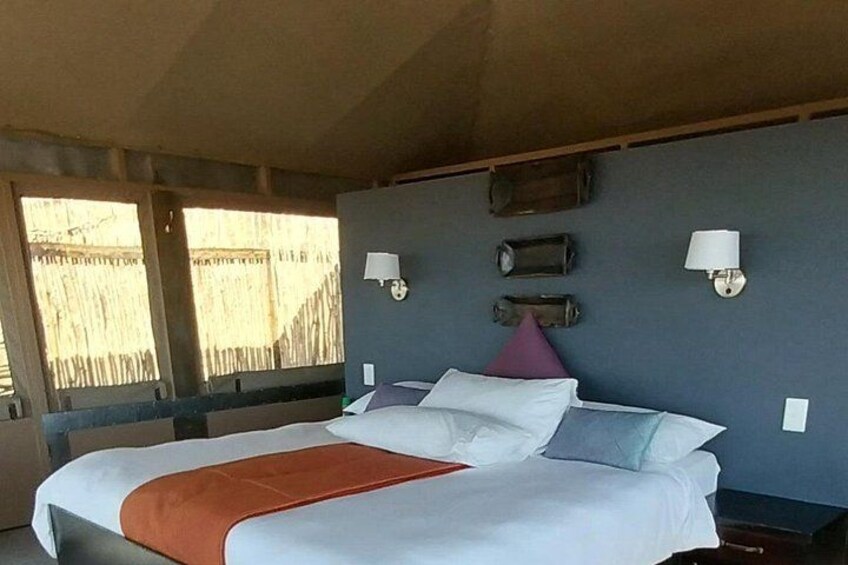 A bed with white linens and a red blanket, two wall-mounted lamps, and a wooden headboard. 5