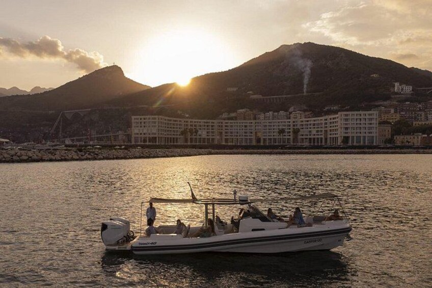 A boat on calm water with a mountain and buildings in the background. 3