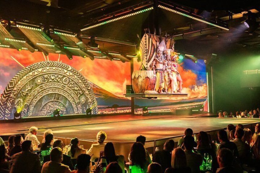Un escenario con una amplia audiencia, un fondo con un gran arco y un grupo de personas en una tarima. 2