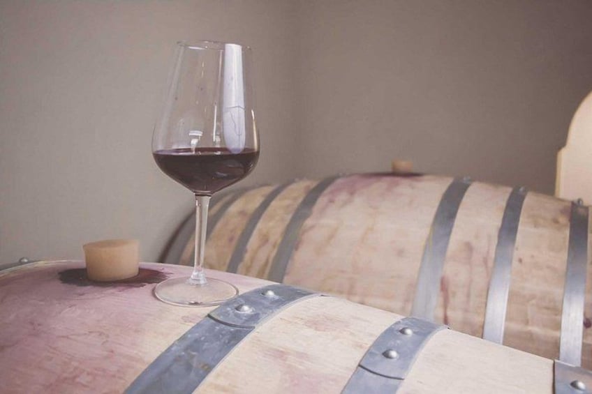 Una copa de vino tinto, una vela y un barril con anillos metálicos. 2