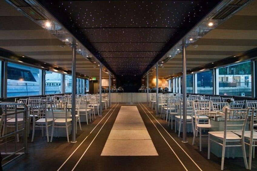 A spacious dining area with rows of tables and chairs, large windows, and a starry ceiling. 2