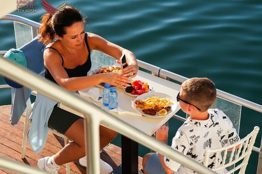 A woman and a child dining at a table by a body of water. 4