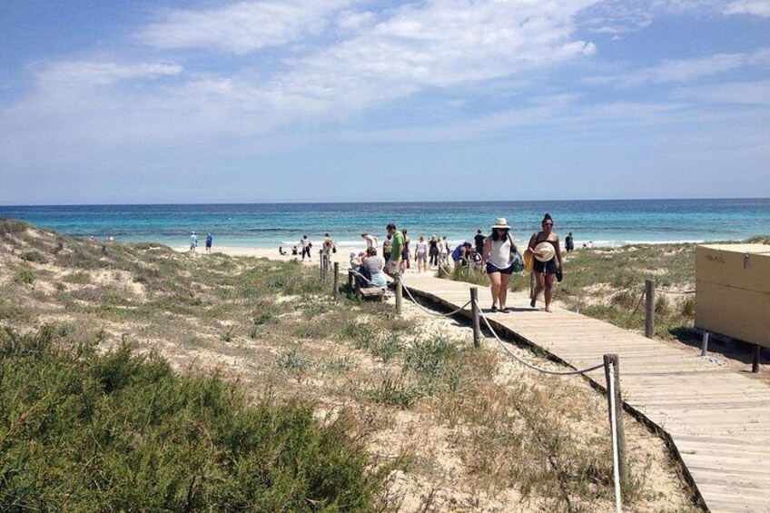 Une plage avec une promenade en bois, des gens qui se promènent et l’océan en arrière-plan. 2