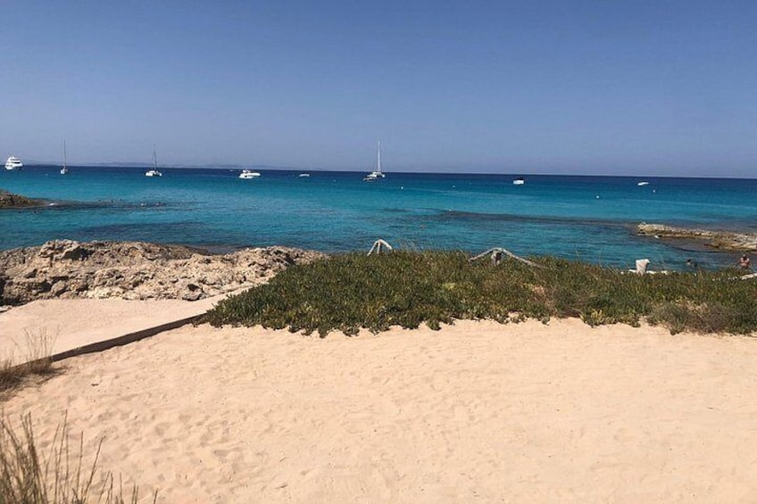 Une plage à l’eau turquoise et limpide, avec des bateaux et des affleurements rocheux. 4