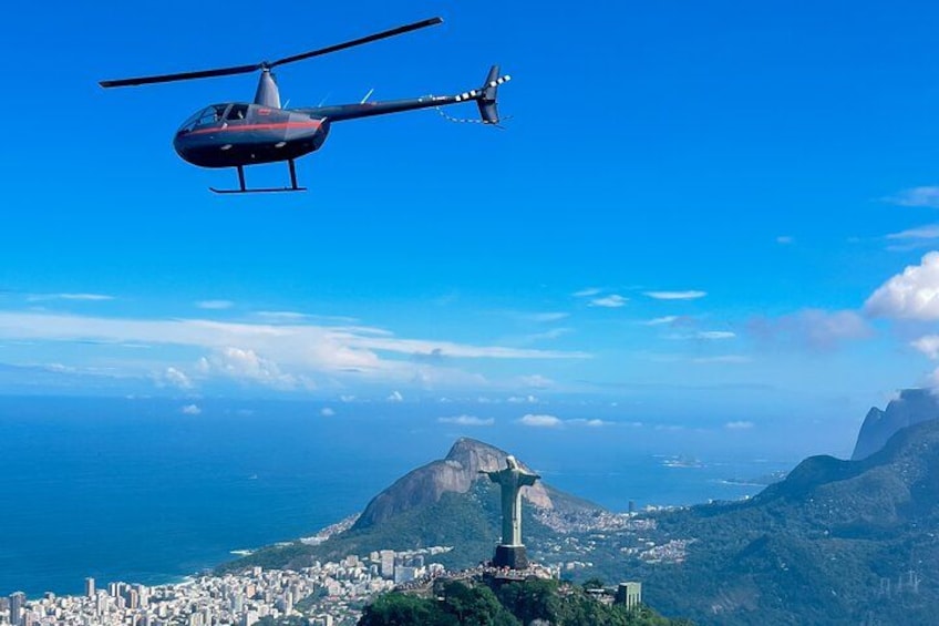 Ein Hubschrauber fliegt über einer Stadt, im Hintergrund erhebt sich ein markanter Berg. 1