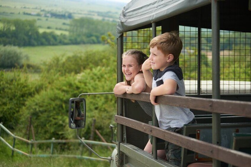 Children leaning out of a vehicle window, overlooking a green landscape. 3