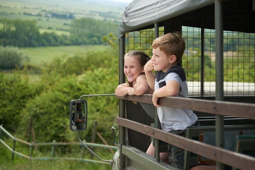 Two children leaning out of a bus window, overlooking a green landscape. 2