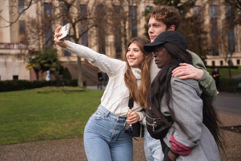 Three people taking a selfie in a park with a building in the background. 5