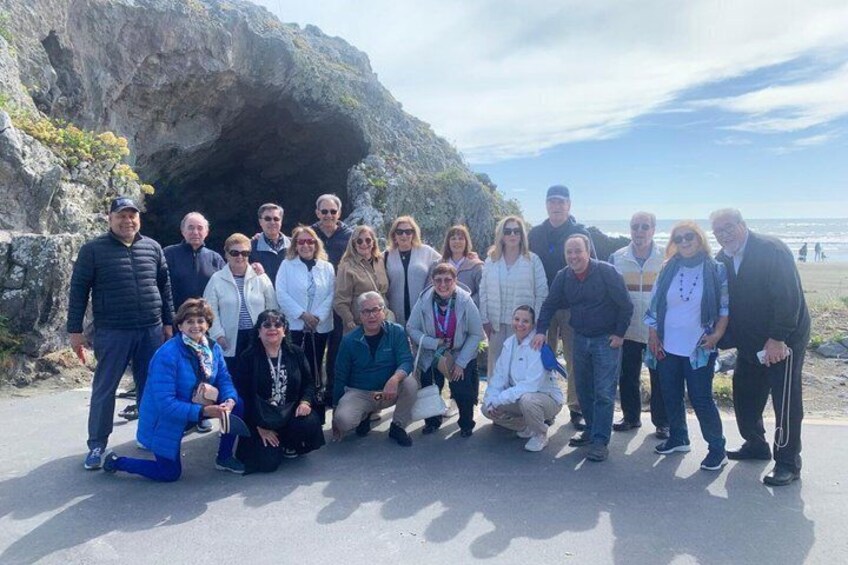Eine Gruppe von Menschen posiert vor einer felsigen Küstenlandschaft bei blauem Himmel. 2