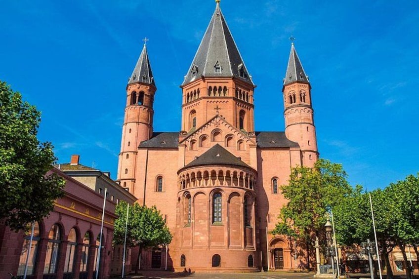 Een grote rode bakstenen kerk met drie torens en een centrale ingang. 3