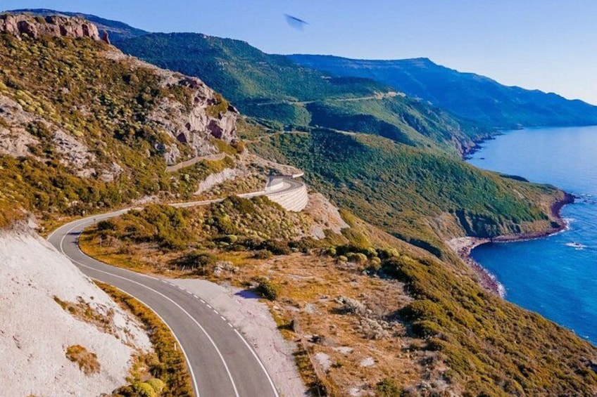 Une route sinueuse qui longe une falaise côtière, offrant une vue sur la mer et les montagnes lointaines. 2