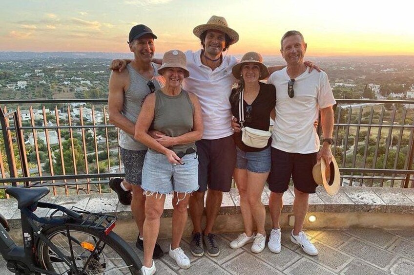 A group of people standing on a balcony with a cityscape in the background. 5