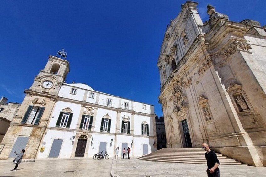 A historic building with a clock tower, a staircase leading to a door, and a person standing in the foreground. 2