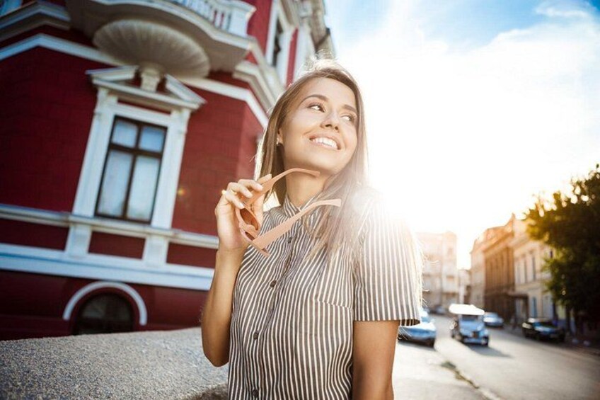 Una persona frente a un edificio rojo con detalles blancos, sosteniendo gafas de sol. 3