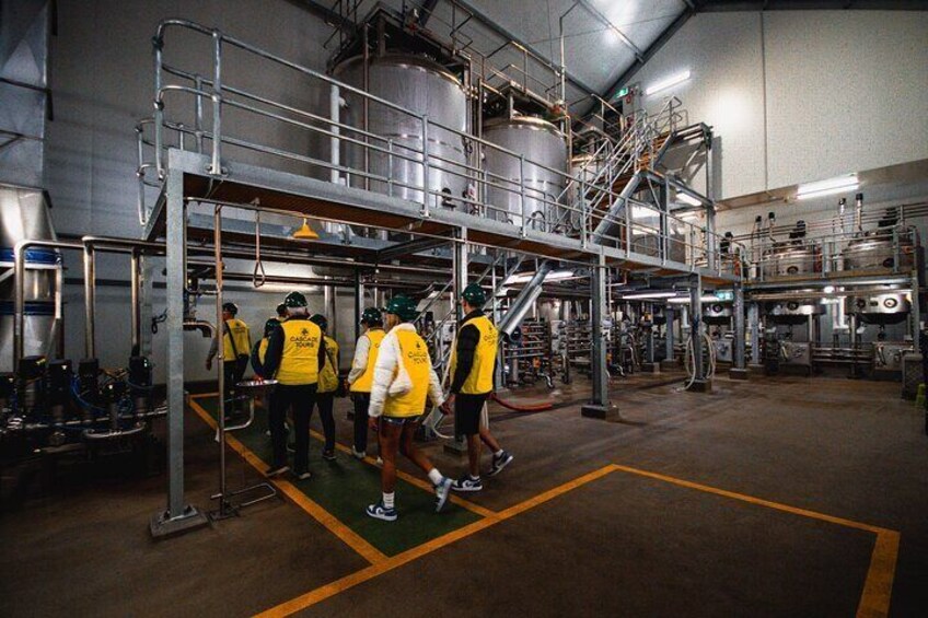 Un grupo de personas en una amplia instalación industrial con estructuras metálicas y maquinaria. 3