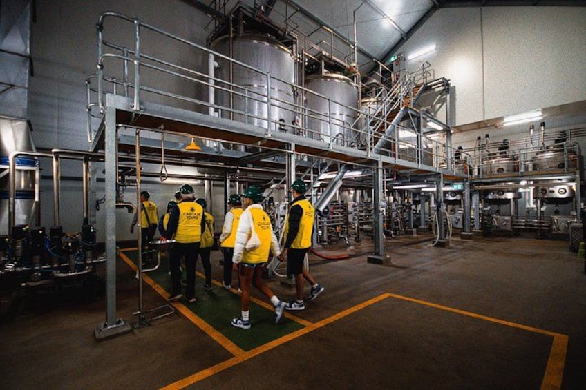 A group of people in a large industrial facility with metal structures and machinery. 2