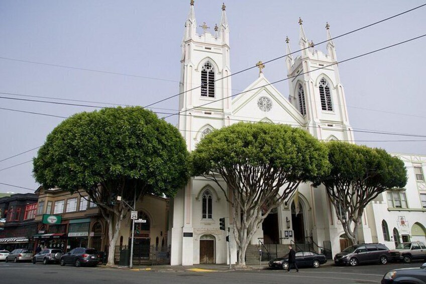 Una iglesia blanca con dos torres y un árbol grande al frente. 3