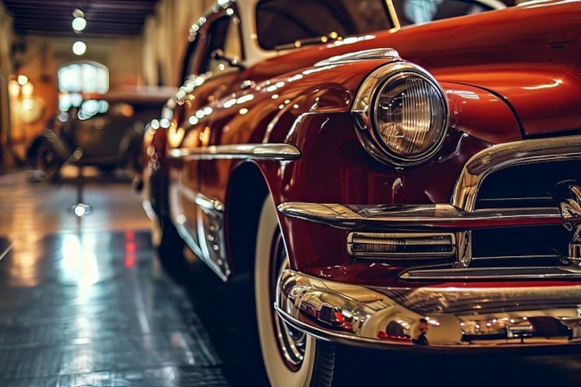 A vintage red car with chrome detailing in a dimly lit garage. 3