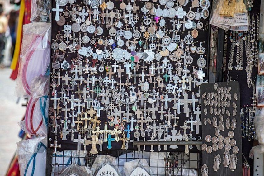 A display of various religious and cultural artifacts, including crosses, medallions, and other symbols, arranged on a wall. 2