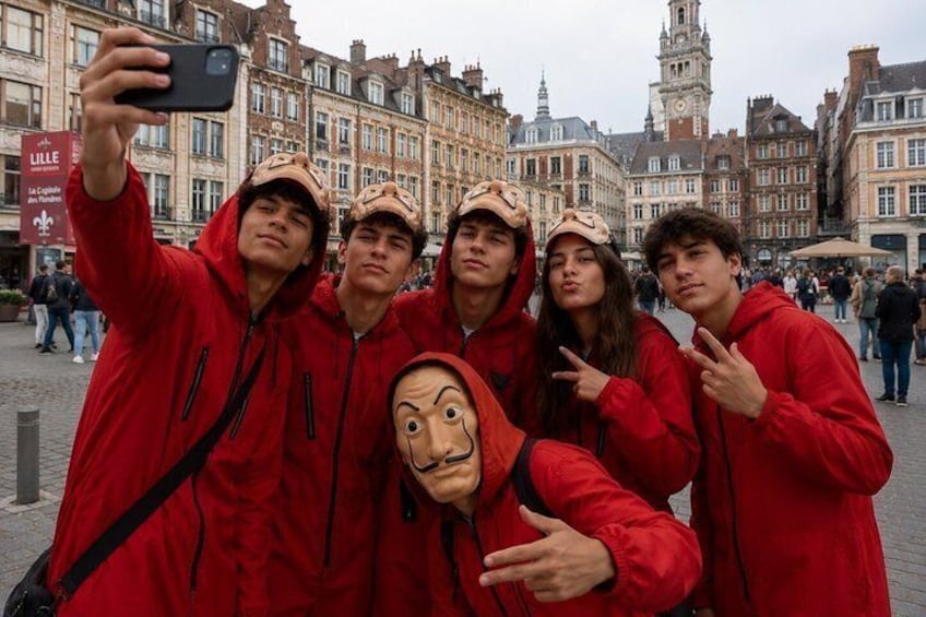 A group of people in red jackets taking a selfie in a city square with historic buildings in the background. 1